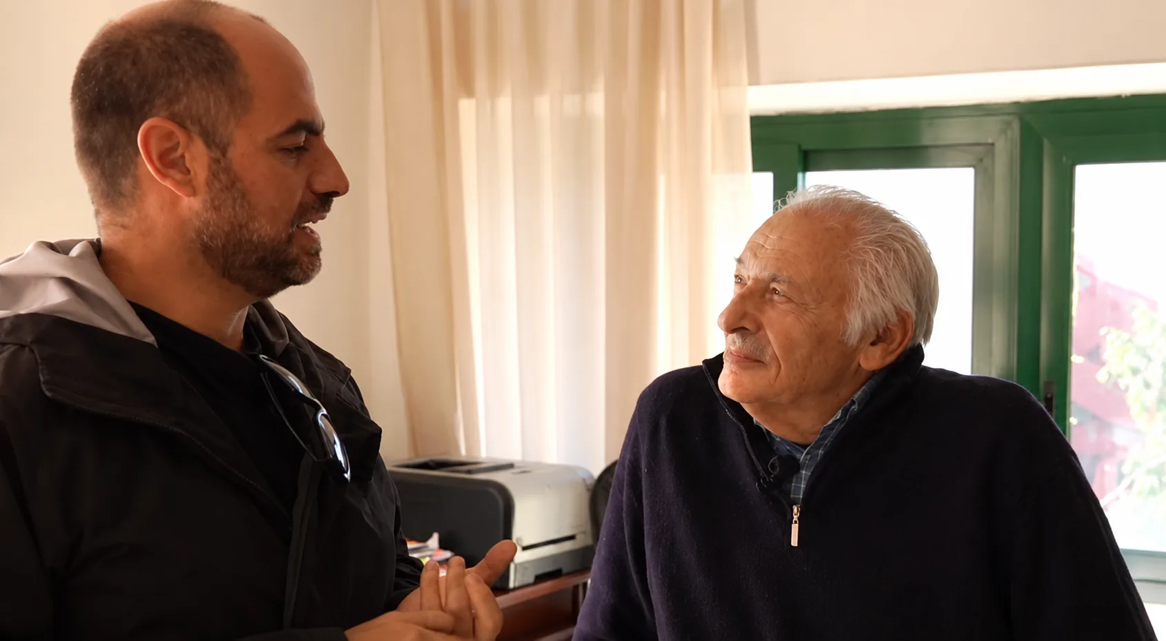 Pietro Mereu conversa con un uomo anziano durante un’intervista